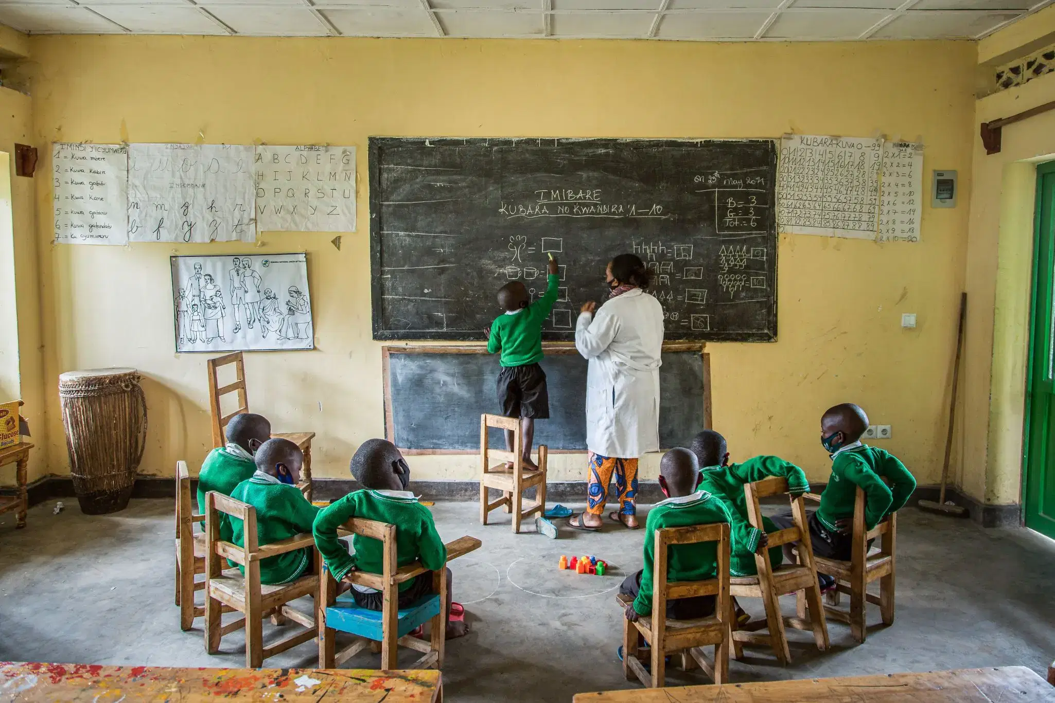 A classroom with a child writing on the blackboard.
